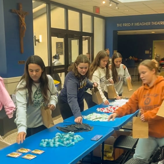 Assembly line of volunteers packaging gift bags for St. Francis Inn