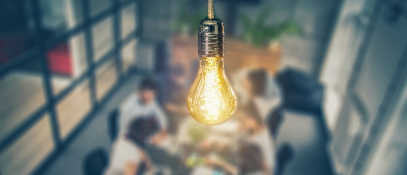 Close up of a light bulb in a room of professionals